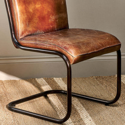Brown leather chair with metal frame on a striped carpet