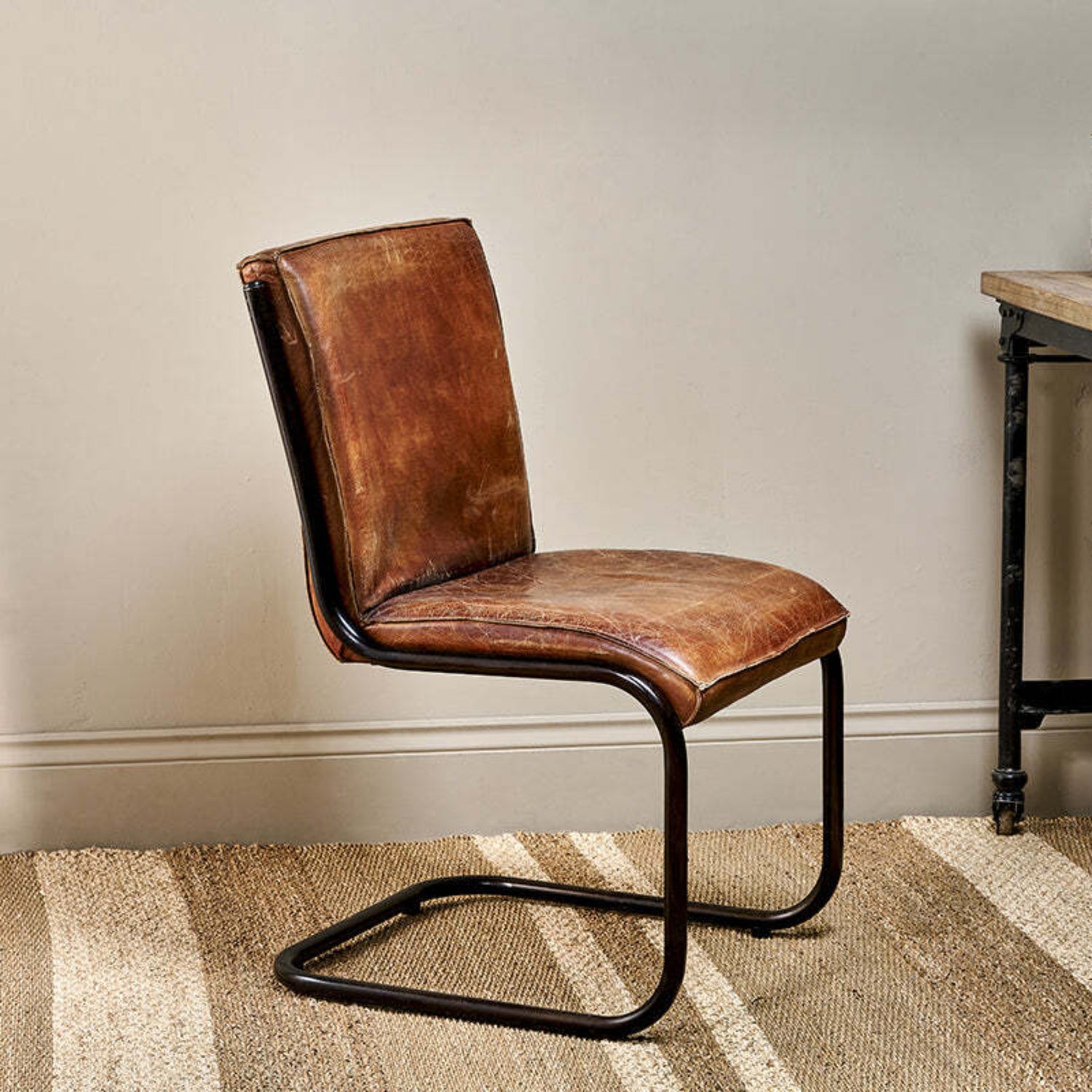 Brown leather chair with black metal legs in a room setting.