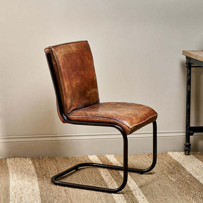 Brown leather chair with black metal legs in a room setting.