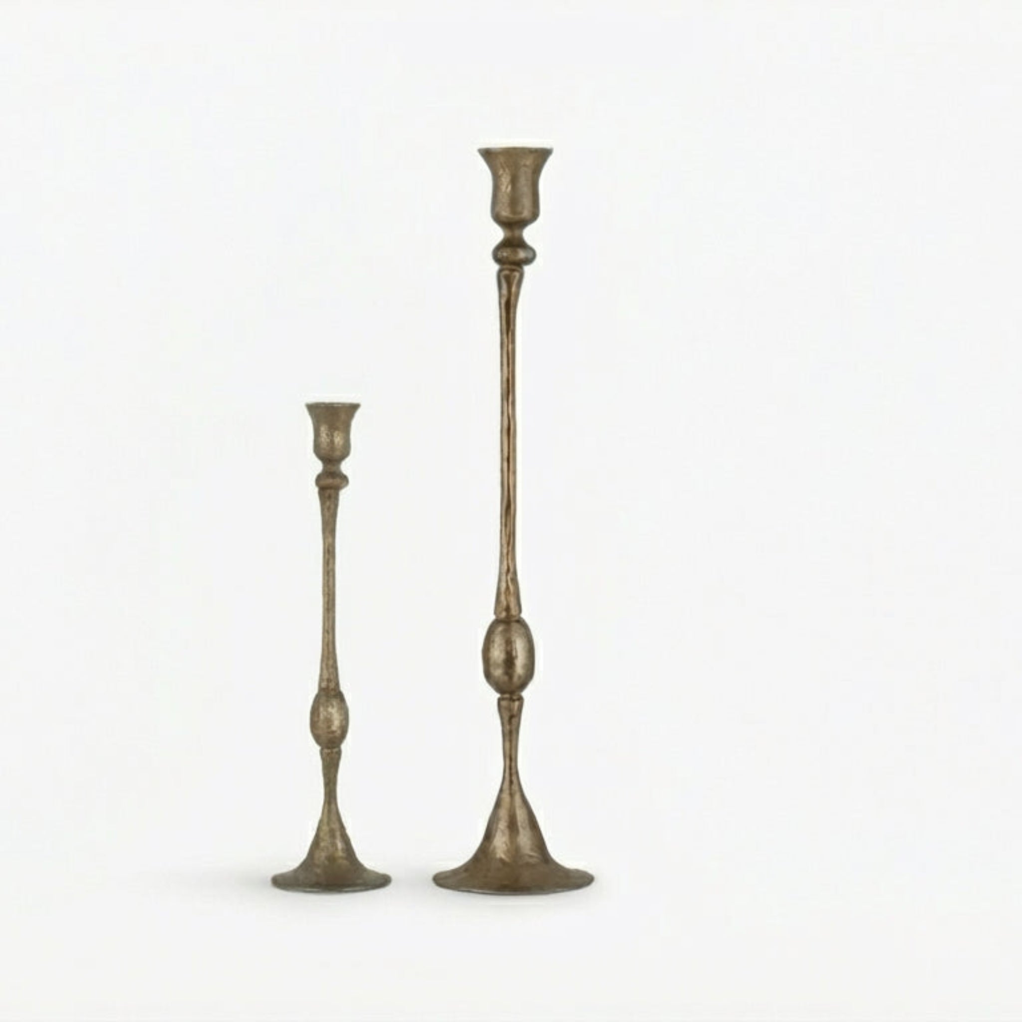 Two tall, ornate candlesticks on a white background