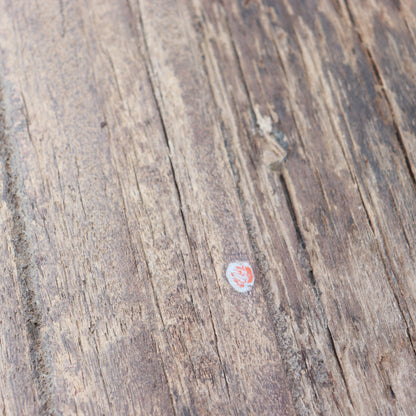 Close-up of a wooden surface with a small red and white label.