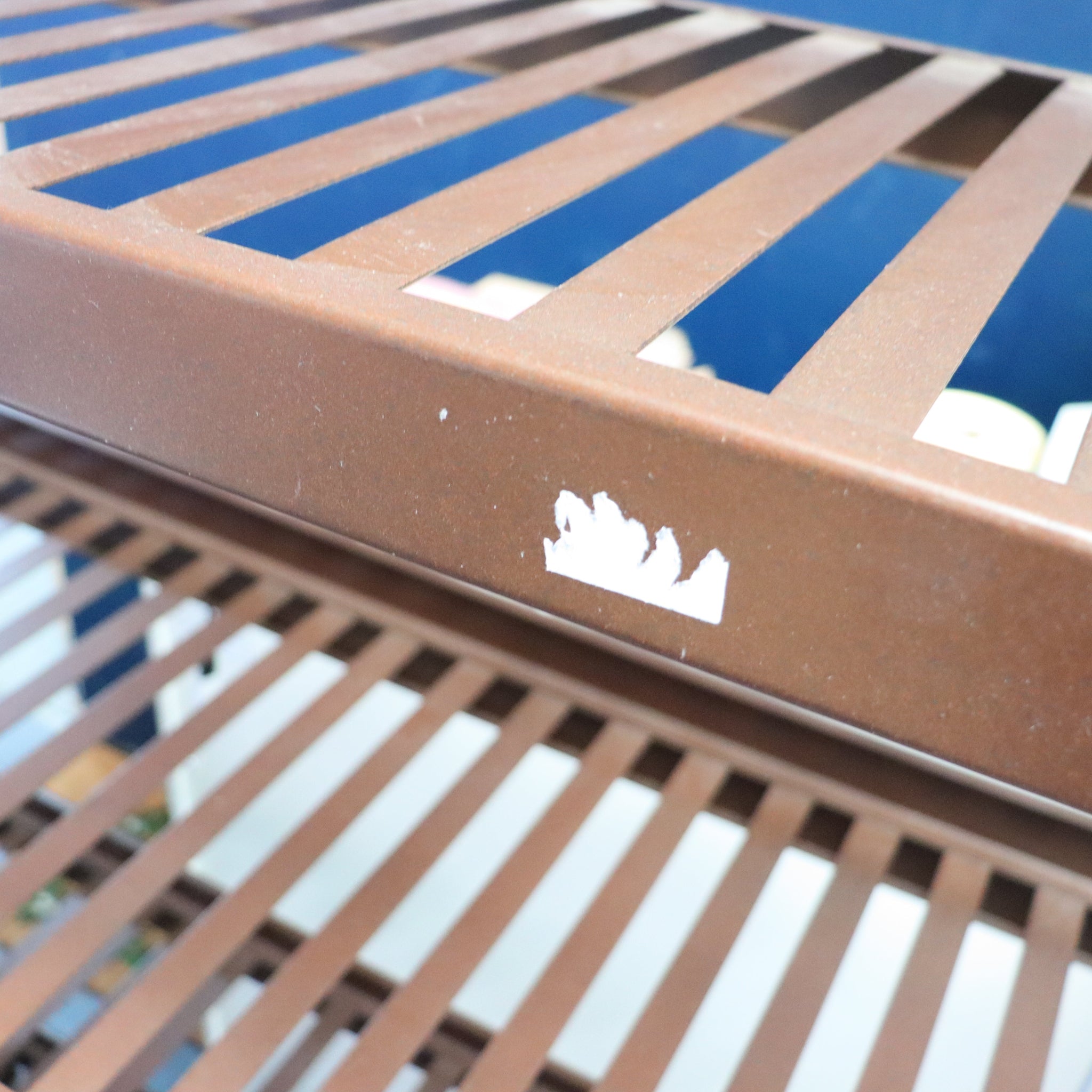 Close-up of a brown metal grate with a logo on a blue background