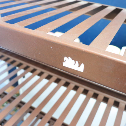Close-up of a brown metal grate with a logo on a blue background