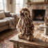 A decorative hawk figurine made from wood and brown and cream jute strands, perched on a small rustic log base on a wooden coffee table in a cozy living room setting.
