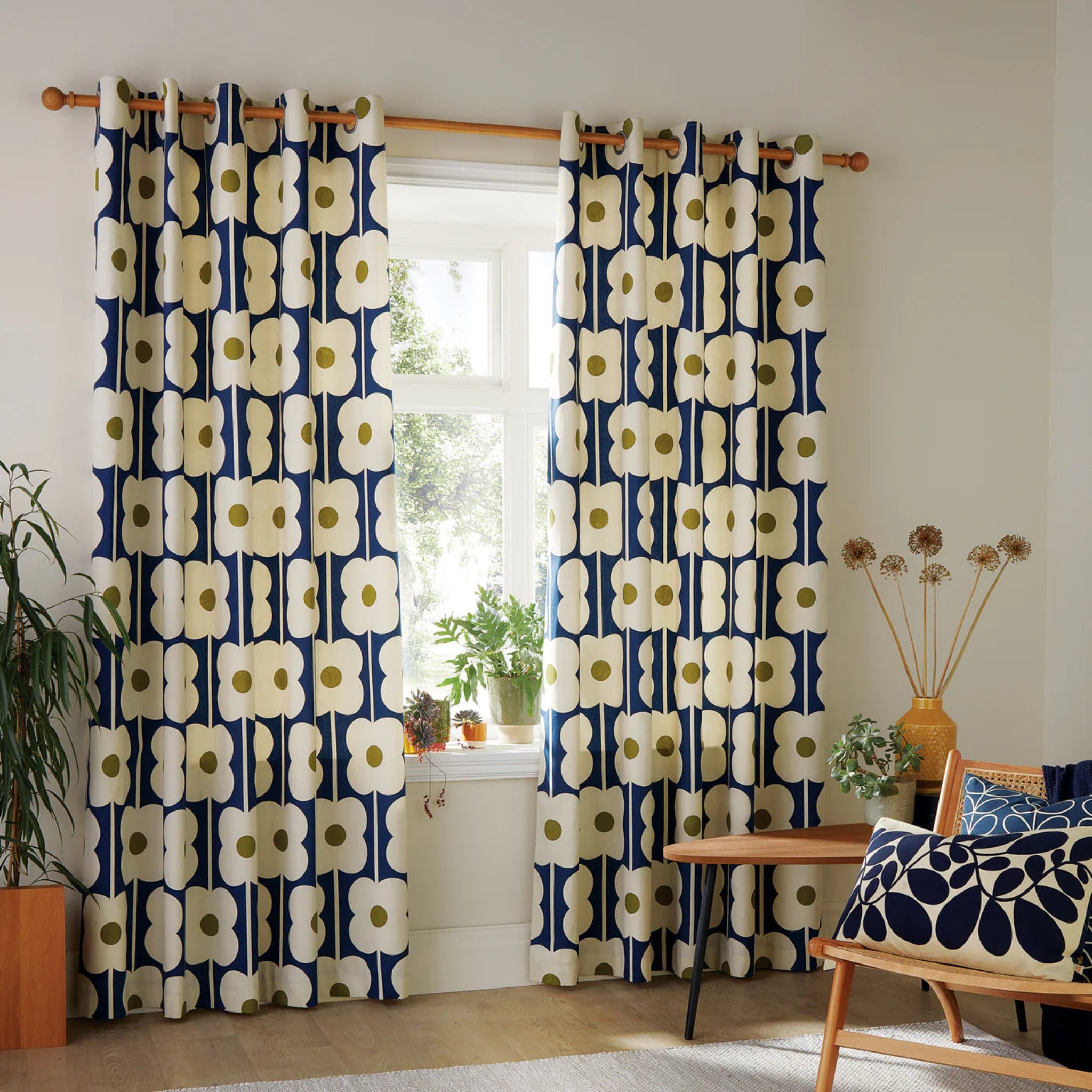 Navy blue and white floral patterned curtains in a room with a desk and plants.