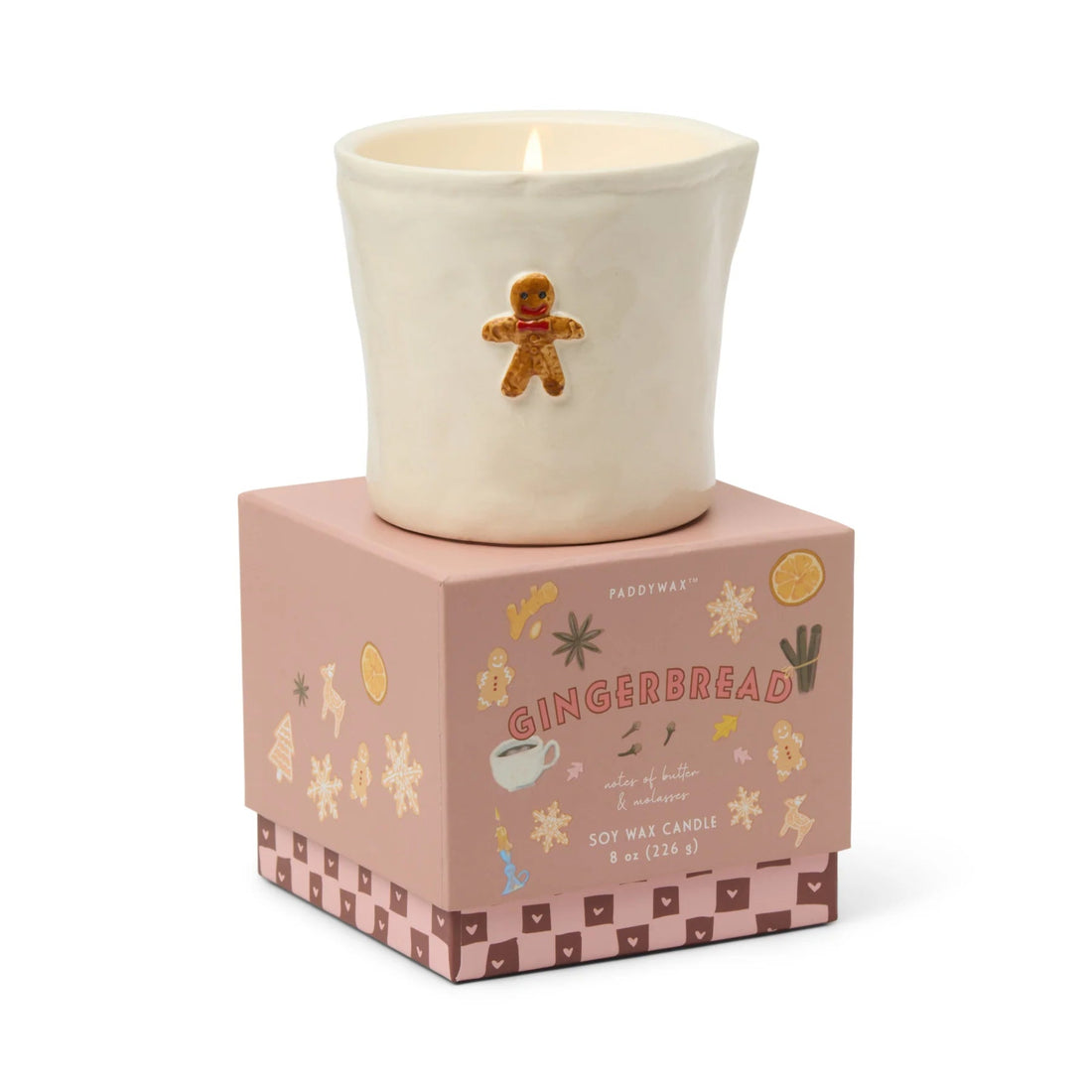Candle in a decorative pot with a gingerbread man design, placed on a matching pink box.