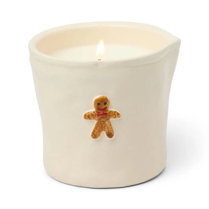 Candle in a white container with a gingerbread man decoration on a white background