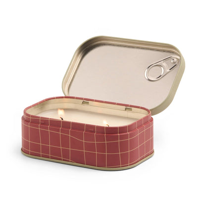 Candle in a red grid-patterned tin can with a metal lid on a white background
