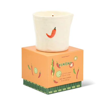 Candle with chili pepper design on a matching box against a white background