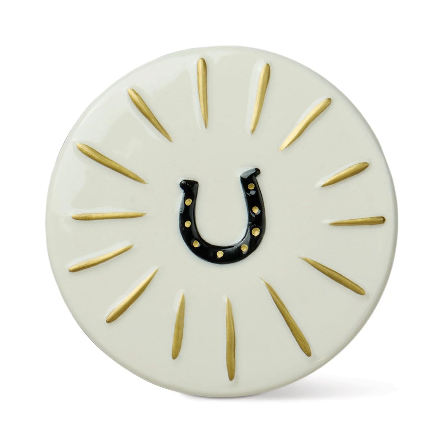 A round off-white decorative plaque or coaster featuring a black horseshoe in the center with small gold dots, surrounded by radiating gold lines on a white background.