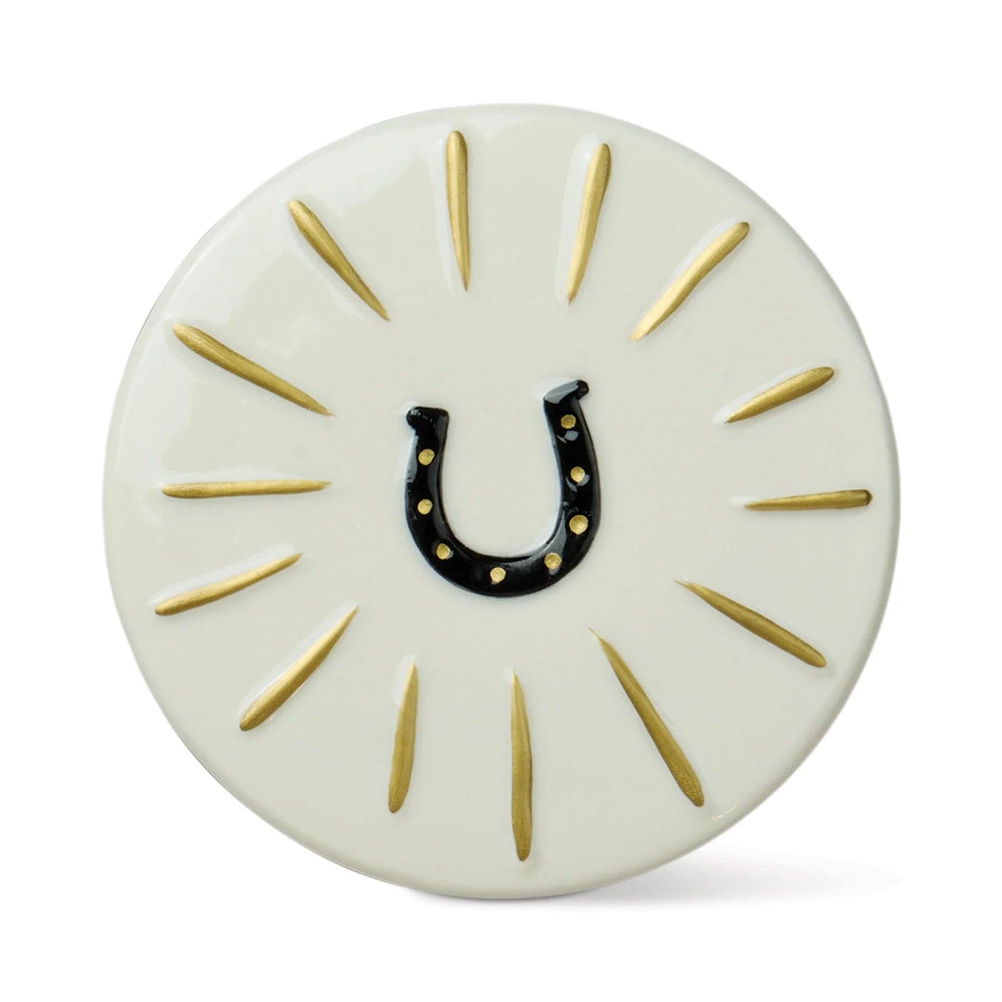A round off-white decorative plaque or coaster featuring a black horseshoe in the center with small gold dots, surrounded by radiating gold lines on a white background.