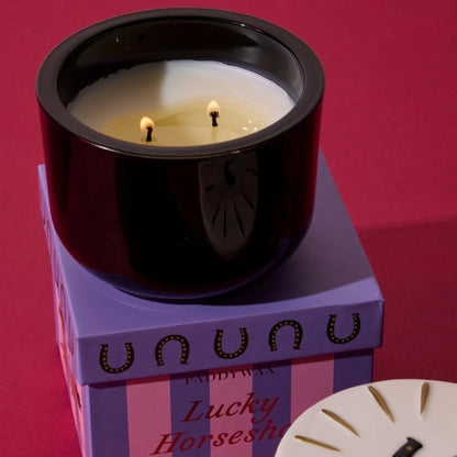 Candle in a black holder with a purple box labeled &