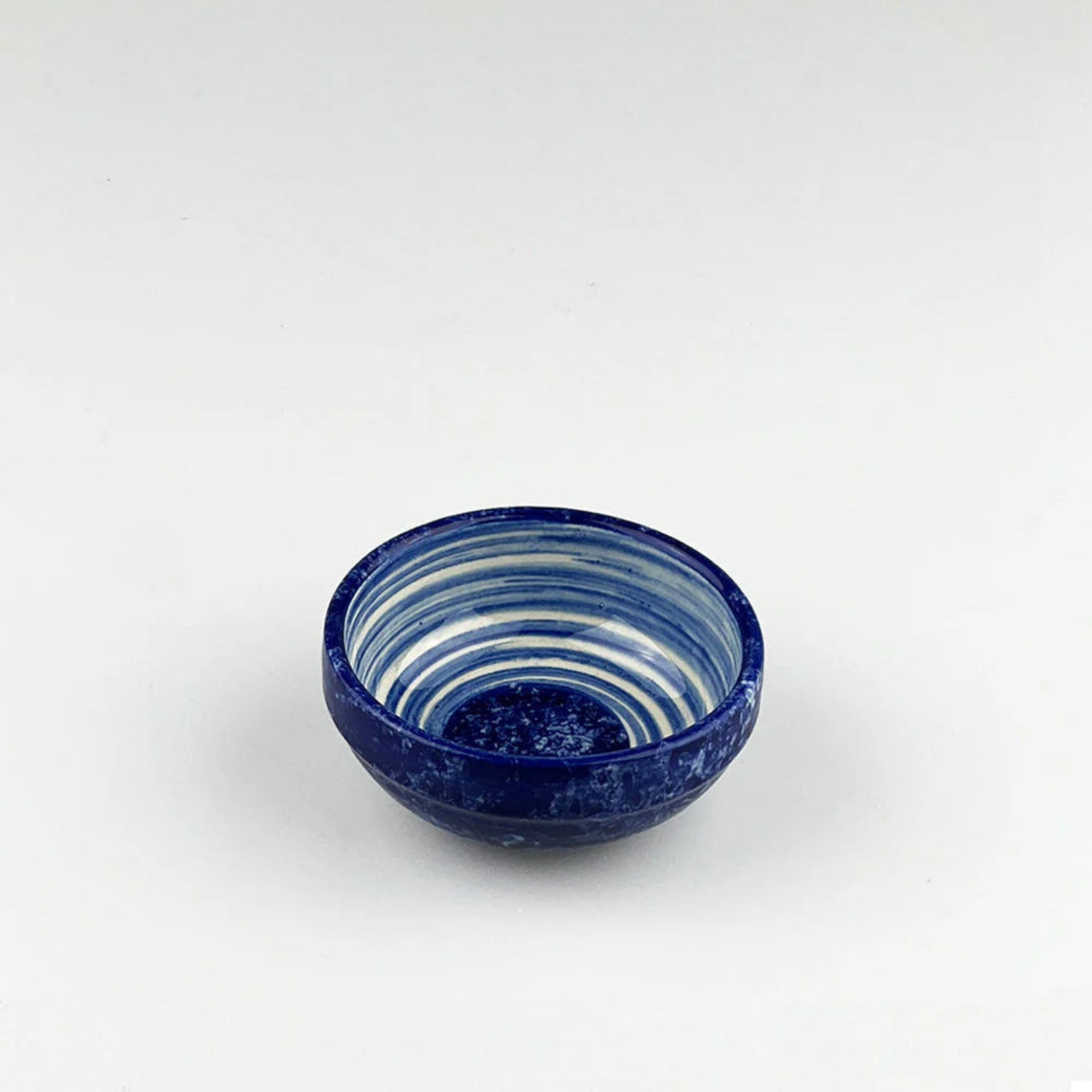 Blue ceramic bowl with white stripes on a white background