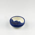 Ceramic bowl with blue exterior and white interior on a light gray background