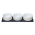 Three small ceramic bowls with white interiors and warm beige exteriors, arranged side by side on a dark rectangular tray against a plain white background.