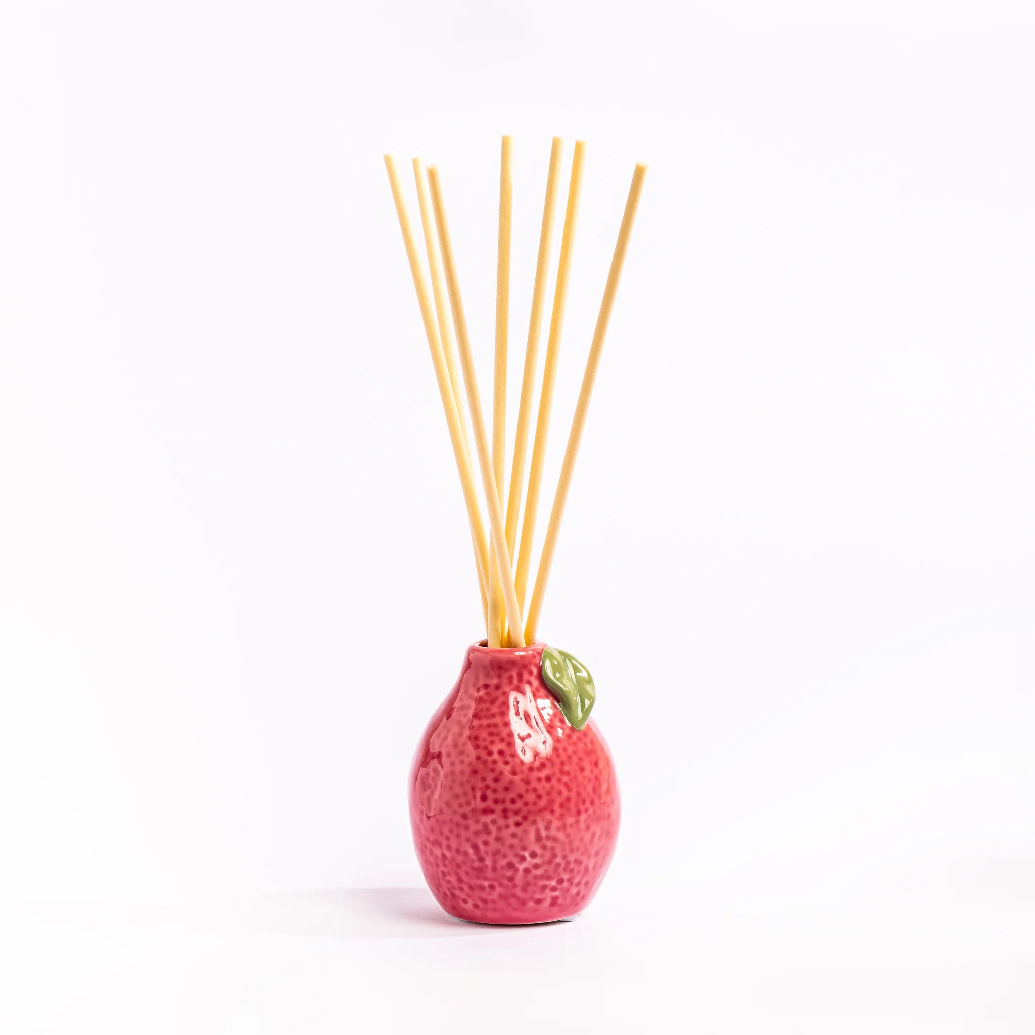 Pink textured diffuser with wooden sticks on a white background