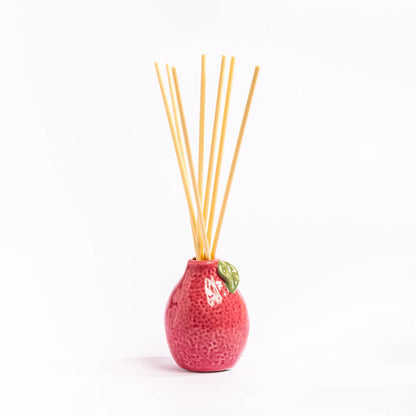 Pink textured diffuser with wooden sticks on a white background