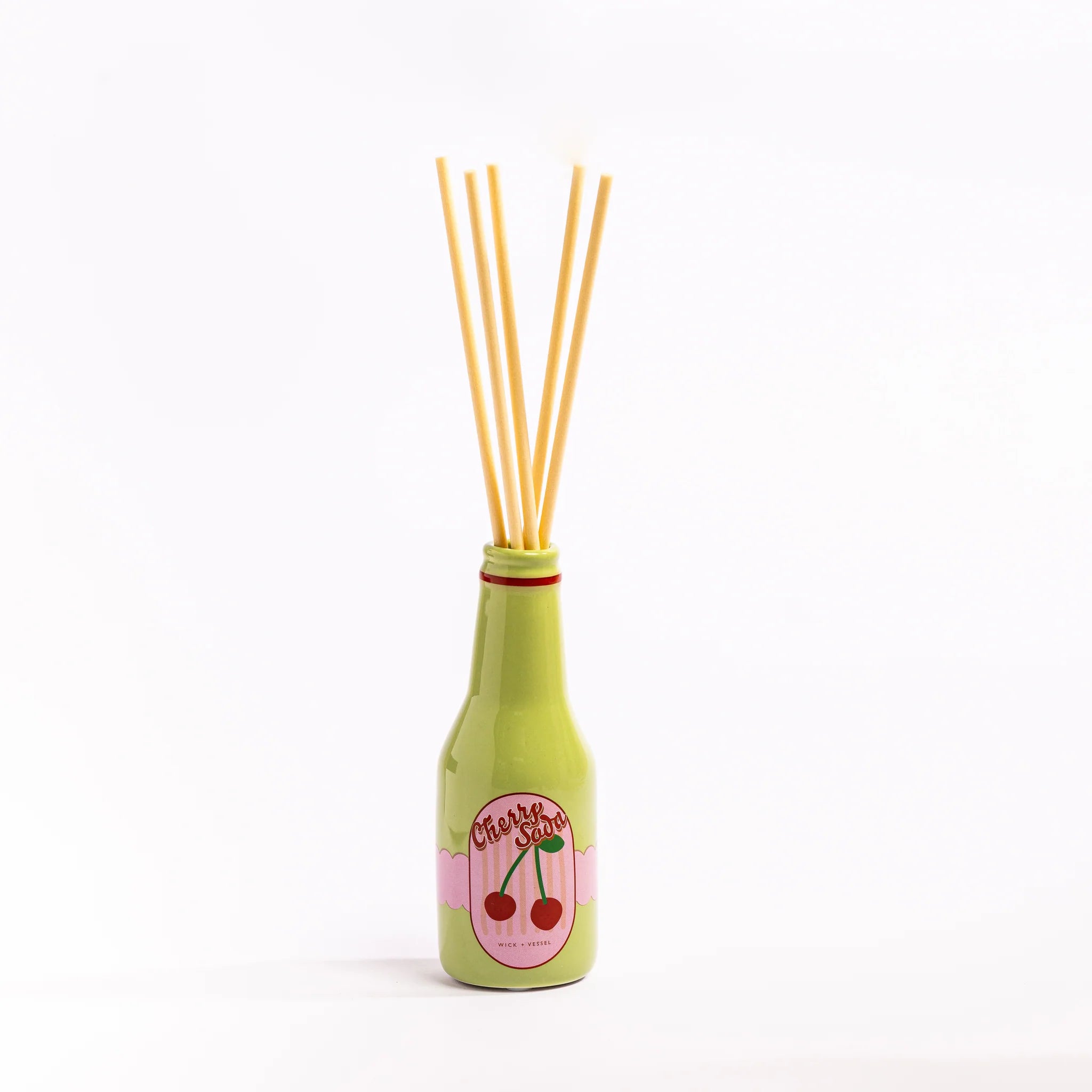 Green bottle-shaped diffuser with wooden sticks on a white background