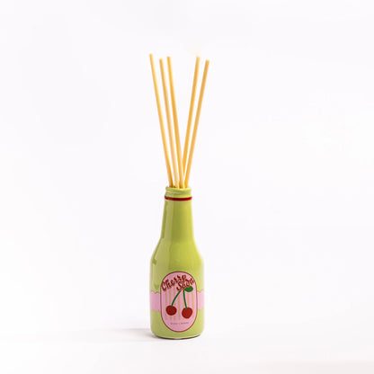 Green bottle-shaped diffuser with wooden sticks on a white background