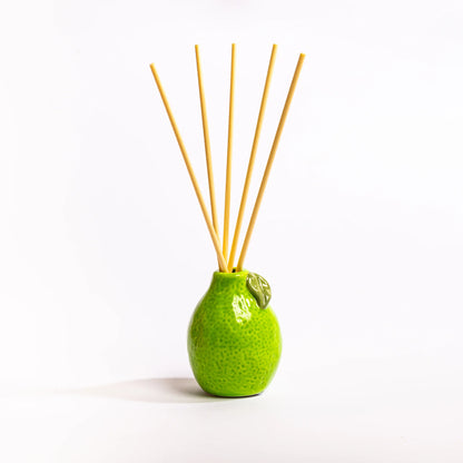 Green ceramic diffuser with wooden sticks on a white background