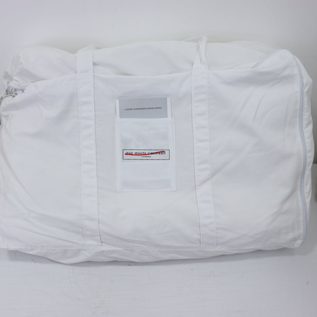 White quilted jacket with a brand label on a light gray background