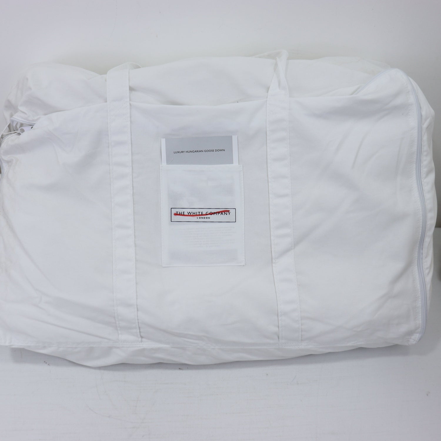 White quilted jacket with a brand label on a light gray background