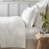 Neatly made bed with white bedding in a bedroom setting.
