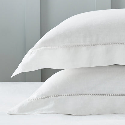 Two white pillows stacked on a bed with a light gray wooden headboard.
