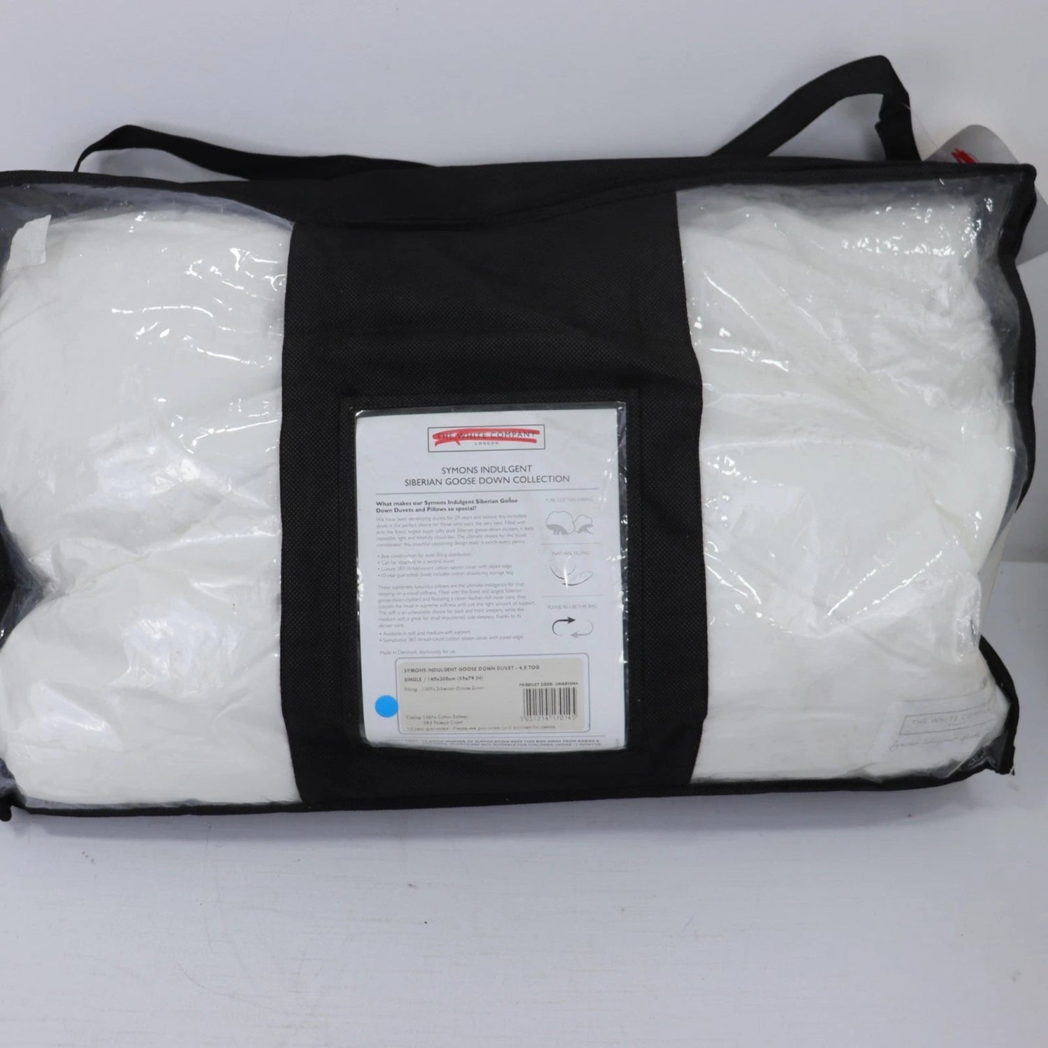 Packaged white pillows in a black carrying bag with a label on a white background