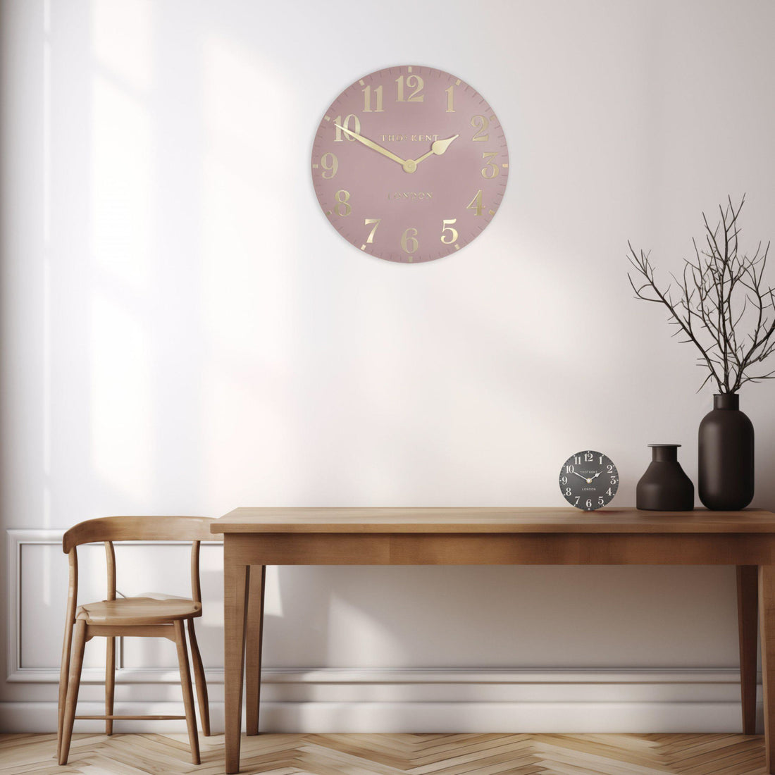 Wall clock on a white wall above a wooden table with decorative items.
