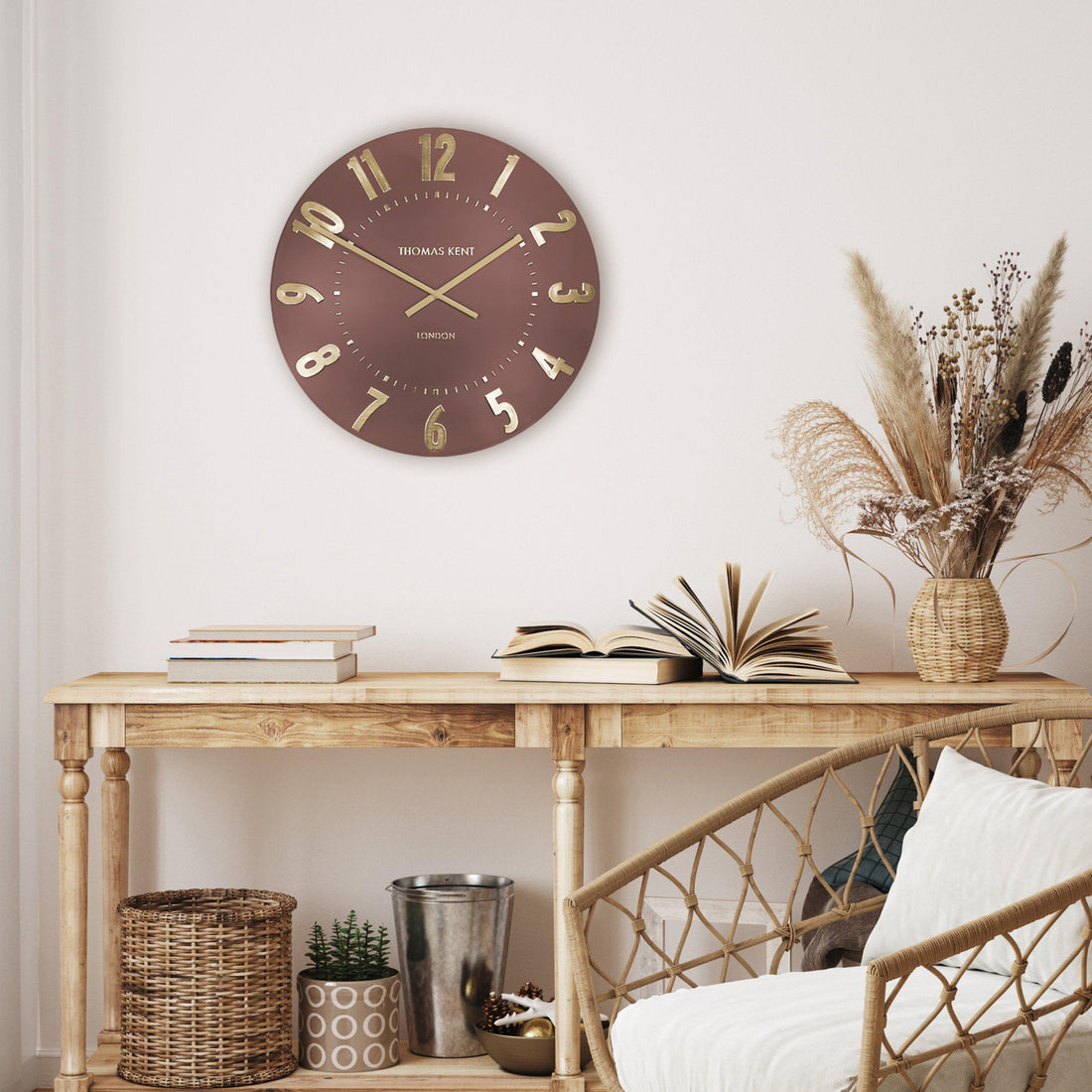Wall clock on a wooden console table with decorative items in a room setting