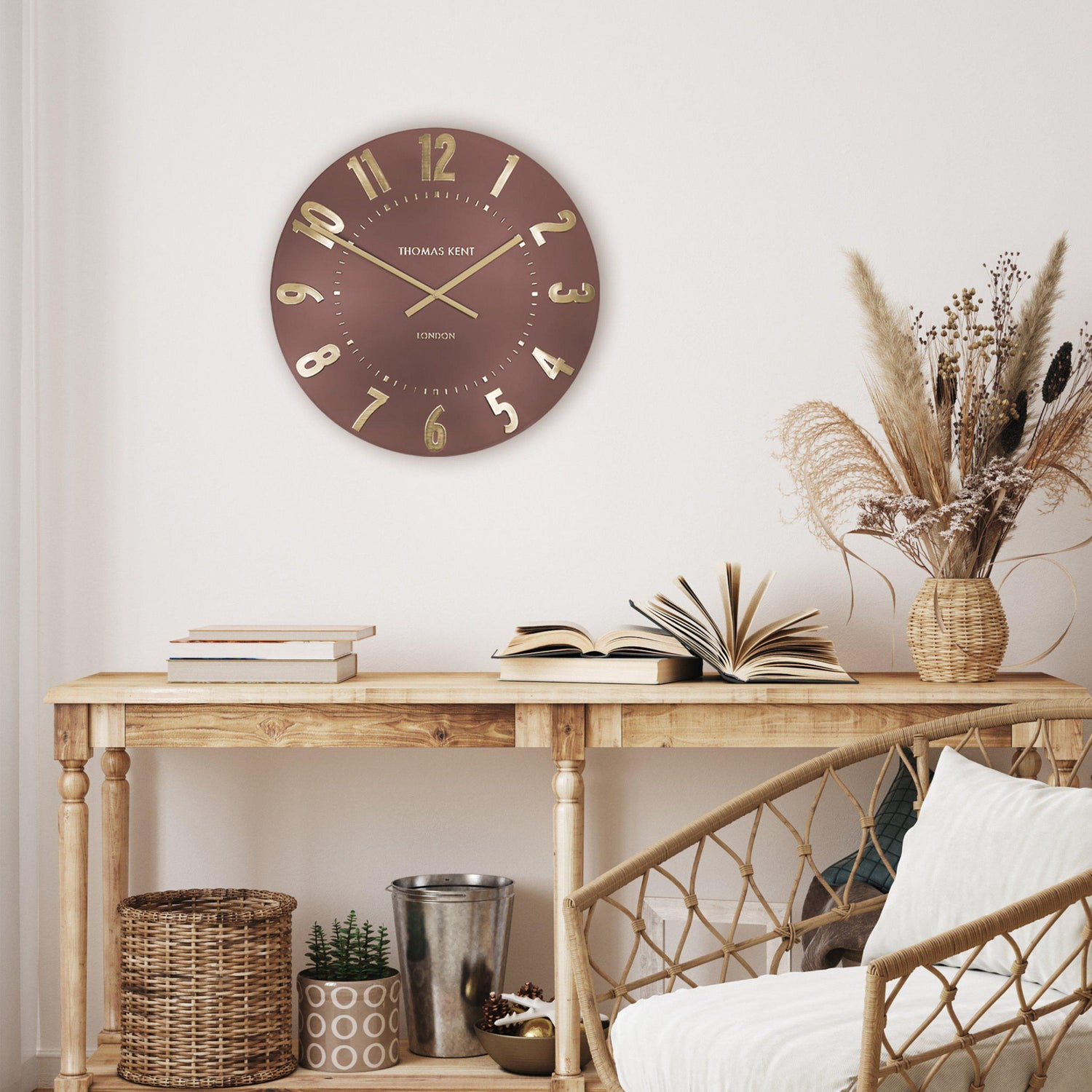 Wall clock on a wooden console table with decorative items in a room setting