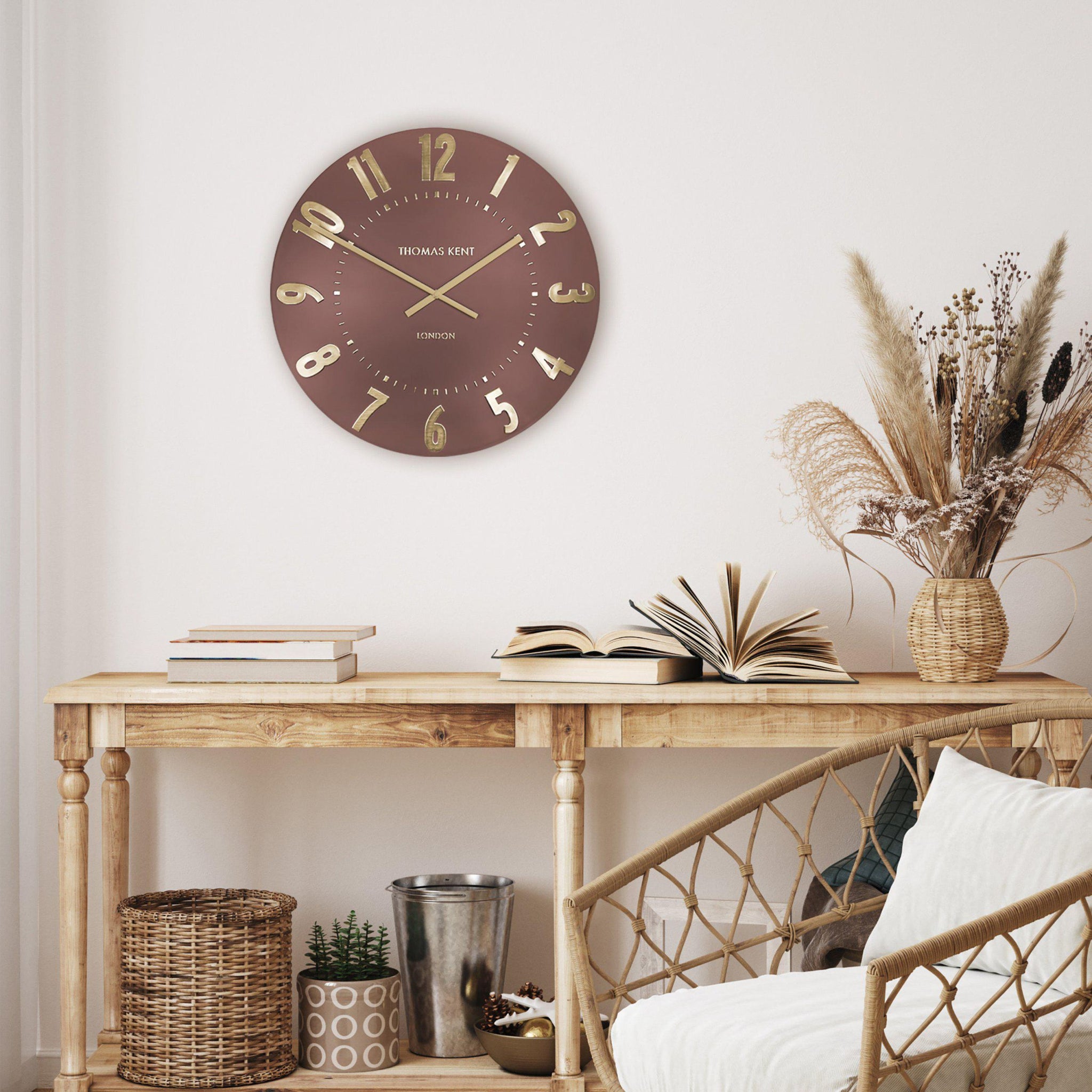 Wall clock on a wooden console table with decorative items in a room setting