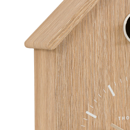 Wooden cuckoo clock with a white face on a white background