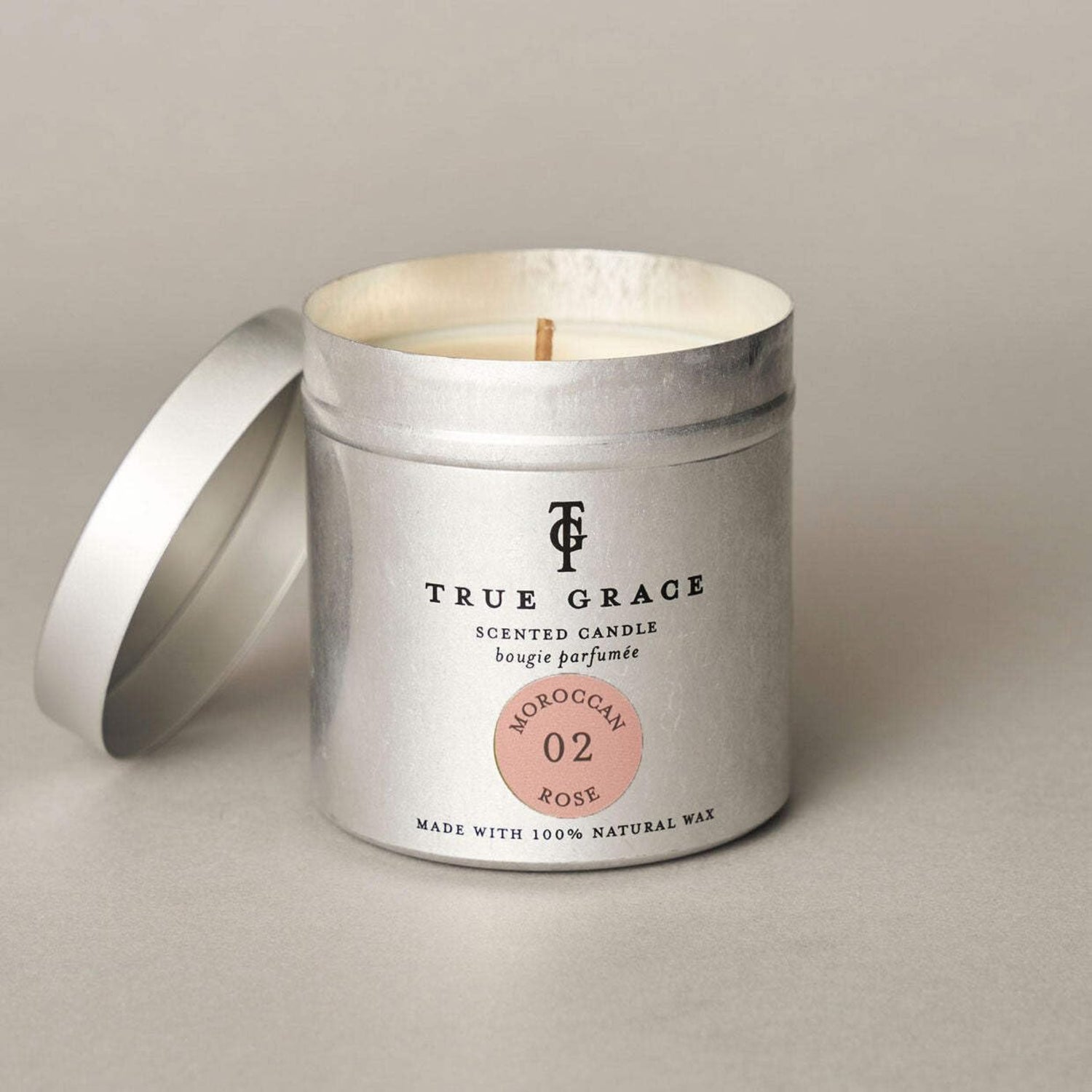 True Grace scented candle in a metal tin on a neutral background