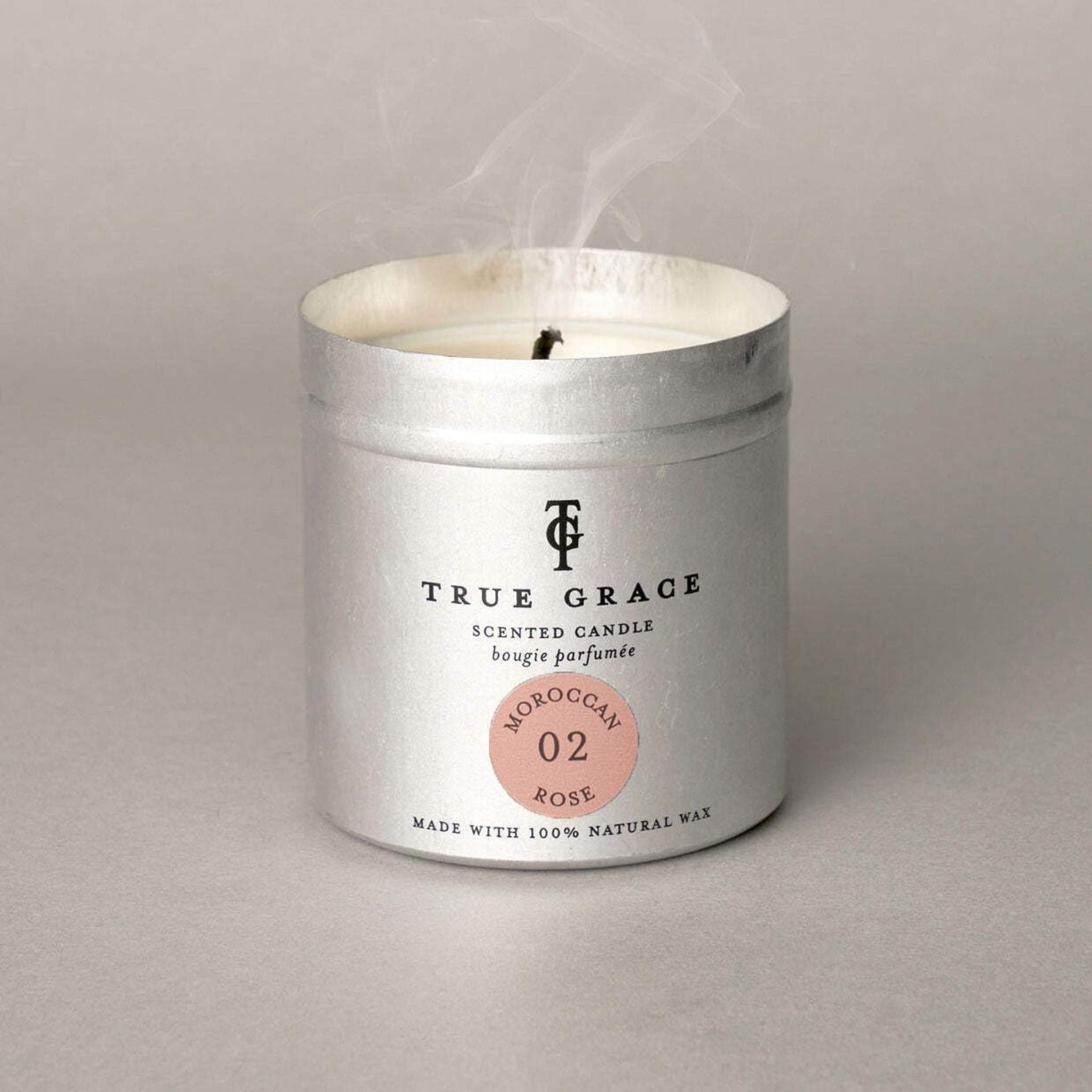True Grace scented candle in a metallic container on a gray background