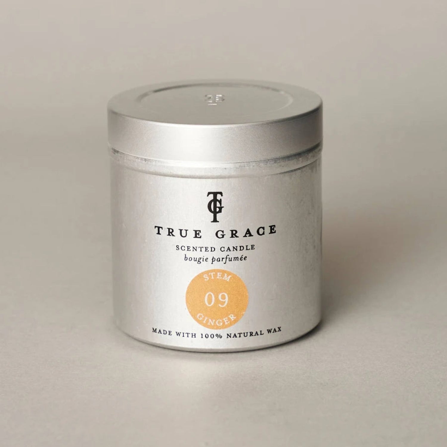 True Grace scented candle in a silver tin on a beige background