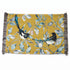 A rectangular woven textile with fringe on both short ends, featuring a mustard yellow background and an illustrated print of two magpies among blue-gray leaves and small birds. A small side tag reads &