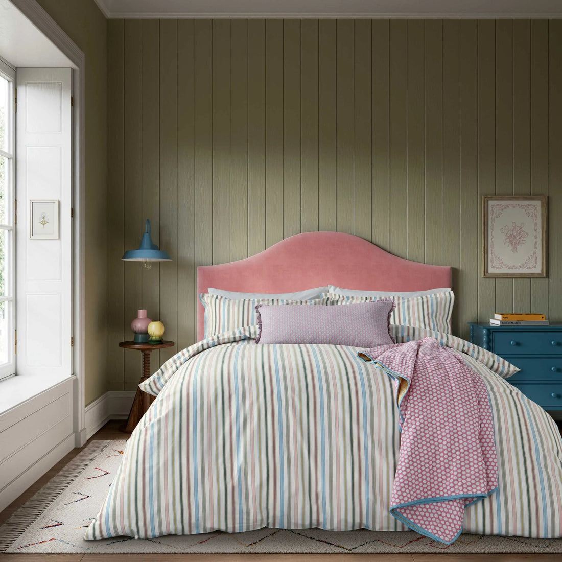 Bedroom with striped bedding and pink headboard