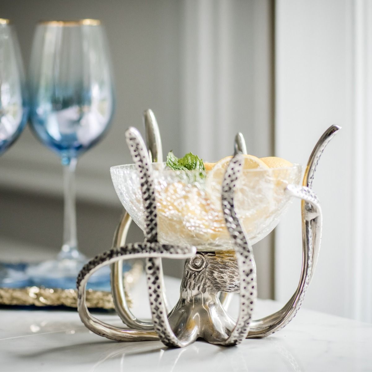 a silver octopus shaped bowl with fruit in it