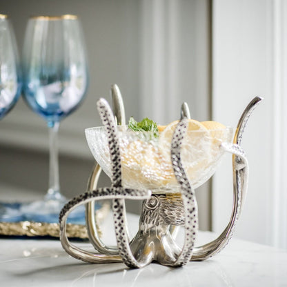 a silver octopus shaped bowl with fruit in it