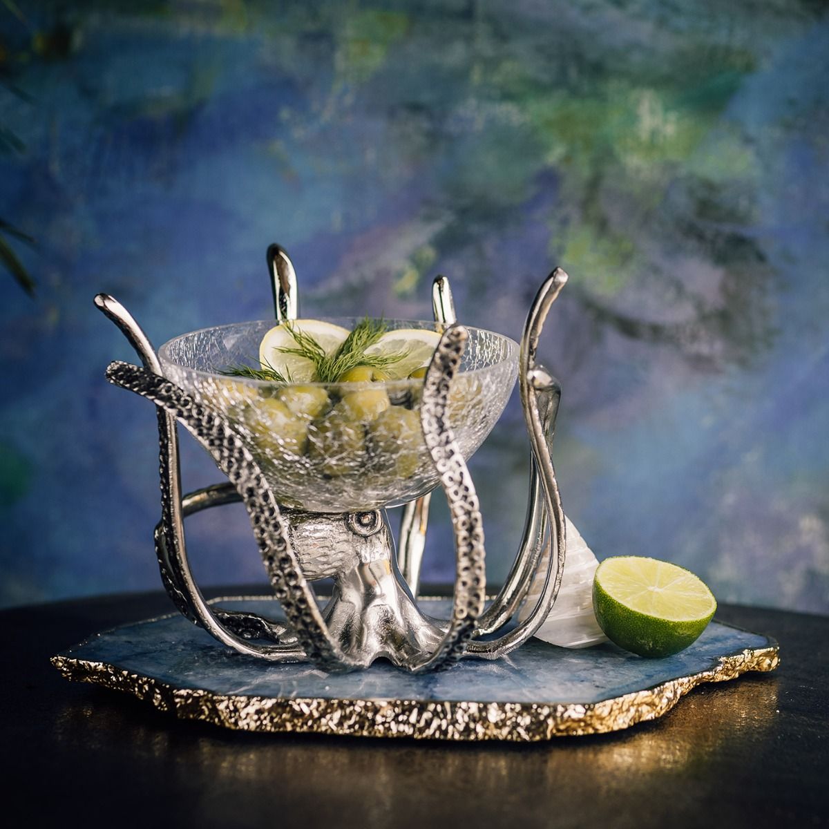 a glass bowl with limes and a slice of lime on a stand