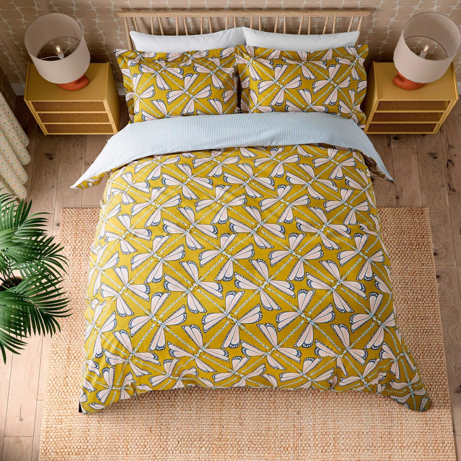 Yellow and white patterned bedding set on a bed with matching pillows, in a room setting.